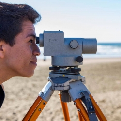 A student making location measurements at a beach